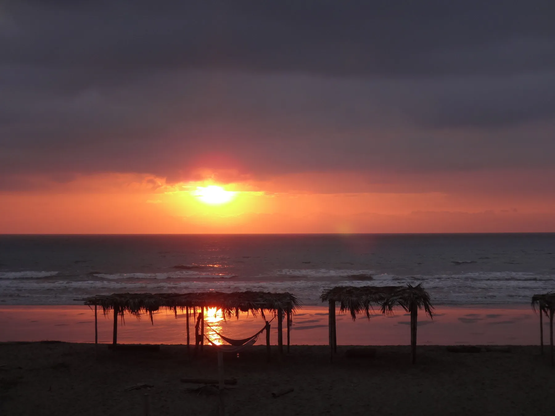 Sunset over the palapas and hammocks on the hotel's private beach in Canoa