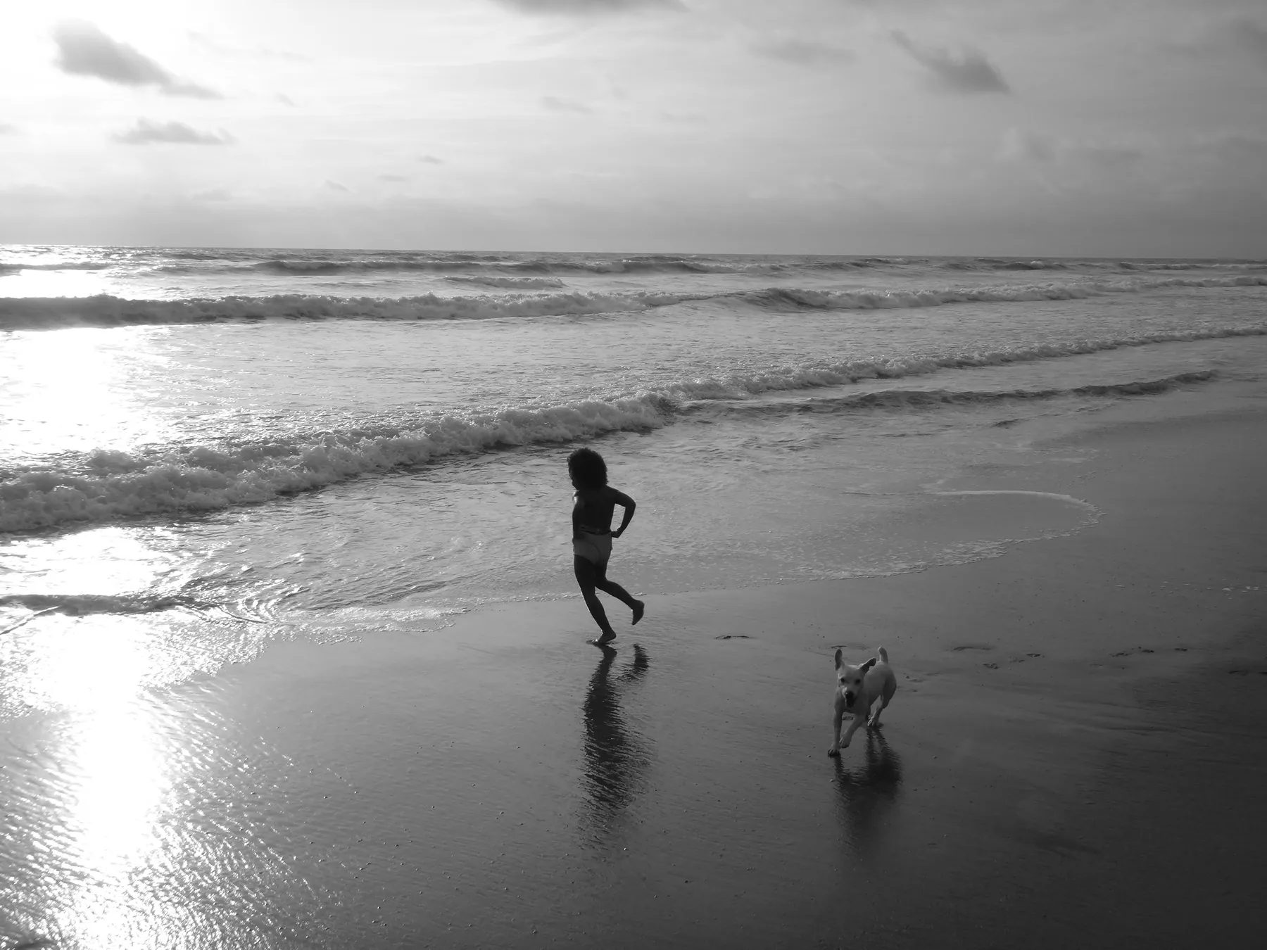 Girl running with a dog along the shoreline in Canoa